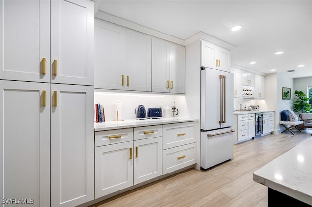 kitchen with white cabinetry, wine cooler, light stone counters, high end fridge, and light wood-type flooring