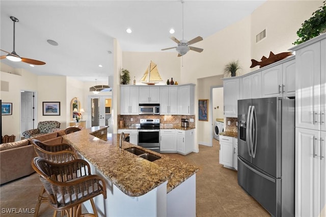 kitchen with stainless steel appliances, washer / clothes dryer, sink, and white cabinets