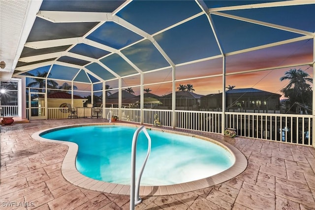 pool at dusk with a lanai and a patio area