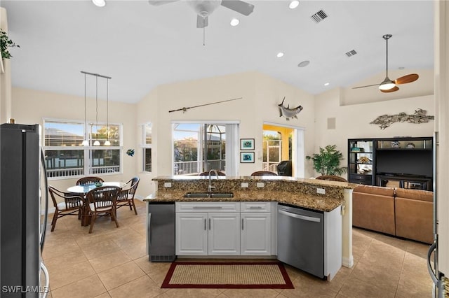 kitchen with appliances with stainless steel finishes, white cabinetry, sink, dark stone counters, and hanging light fixtures