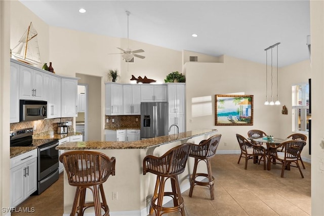 kitchen with pendant lighting, stainless steel appliances, a center island, and white cabinets