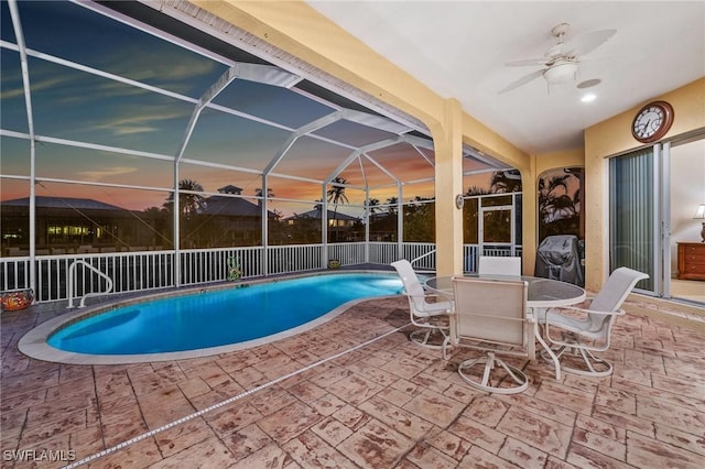 pool at dusk featuring a grill, a lanai, a patio area, and ceiling fan