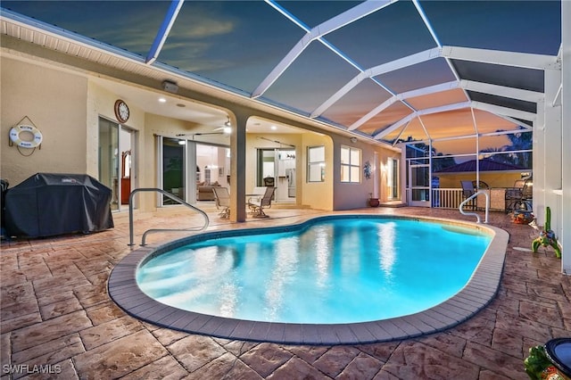 view of pool featuring ceiling fan, grilling area, a patio area, and glass enclosure