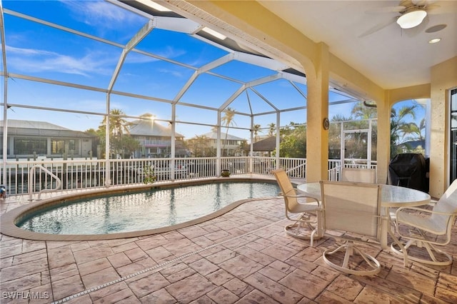 view of pool featuring ceiling fan, glass enclosure, and a patio area