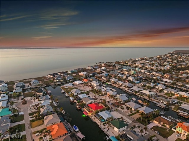 aerial view at dusk featuring a water view