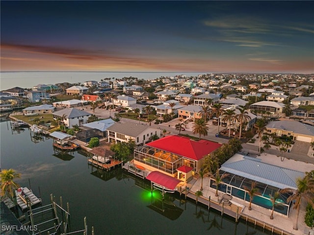 aerial view at dusk featuring a water view