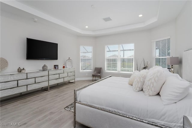 bedroom featuring light wood-type flooring and a tray ceiling