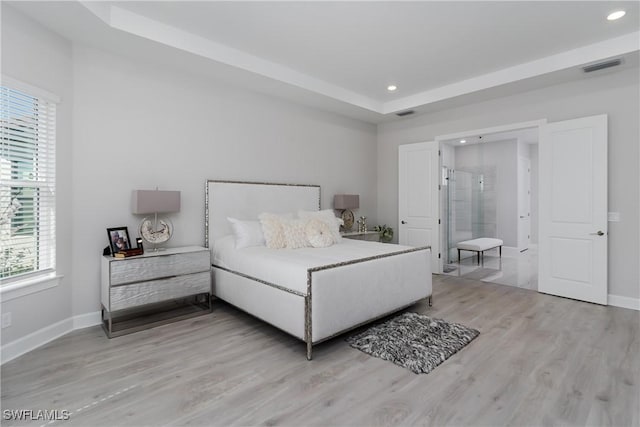 bedroom featuring a raised ceiling and light hardwood / wood-style floors