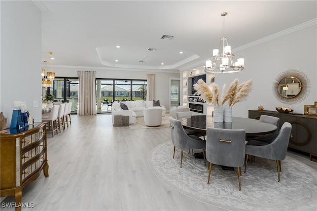 dining space with crown molding, a chandelier, light hardwood / wood-style floors, and a tray ceiling