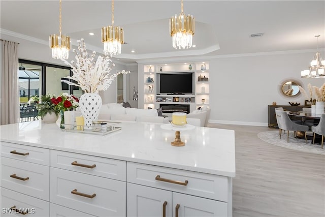 kitchen with white cabinetry, pendant lighting, a notable chandelier, and crown molding