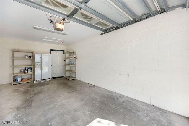 garage featuring a garage door opener and white refrigerator with ice dispenser