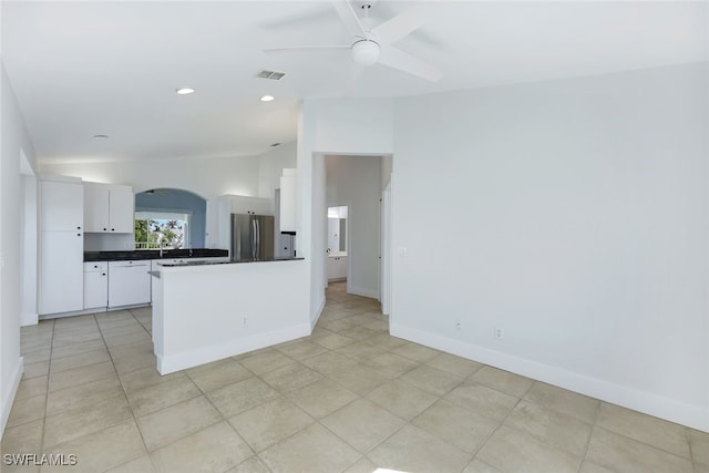 kitchen with vaulted ceiling, light tile patterned flooring, stainless steel refrigerator, white cabinetry, and ceiling fan