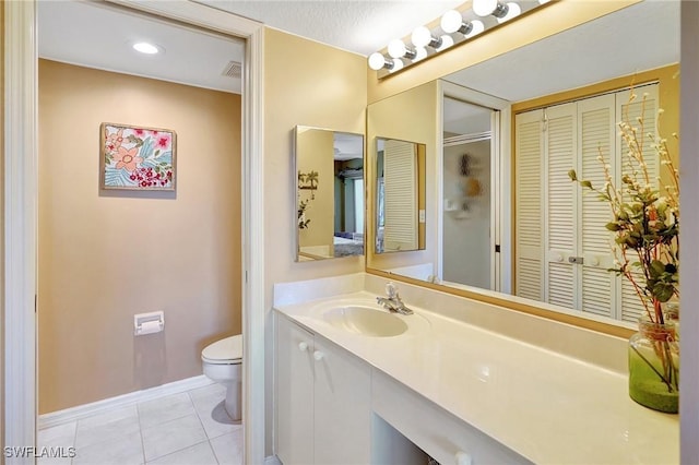 full bathroom with a closet, visible vents, toilet, vanity, and tile patterned flooring