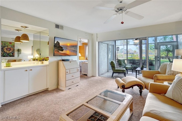 living area with light colored carpet, visible vents, plenty of natural light, and ceiling fan