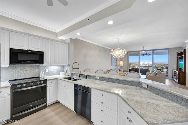 kitchen featuring a peninsula, a sink, black appliances, tasteful backsplash, and crown molding