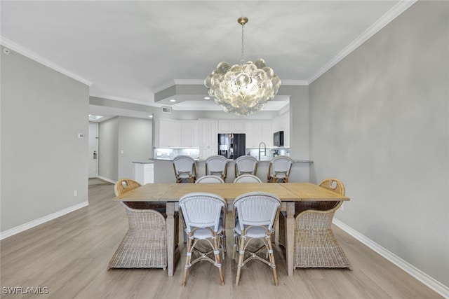 dining space featuring light wood-style flooring, baseboards, a chandelier, and crown molding