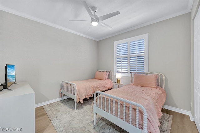 bedroom featuring baseboards, ornamental molding, and wood finished floors