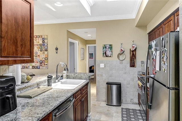 kitchen with sink, tile walls, stainless steel appliances, crown molding, and light stone countertops