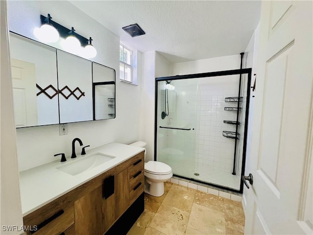 bathroom with a shower with door, vanity, a textured ceiling, and toilet