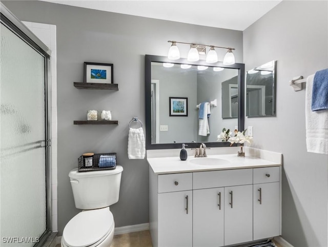 full bathroom featuring toilet, a shower with door, baseboards, and vanity