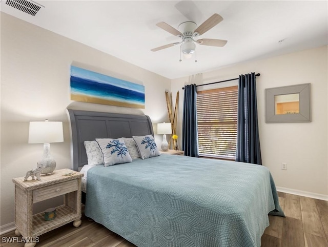 bedroom with a ceiling fan, visible vents, baseboards, and wood finished floors