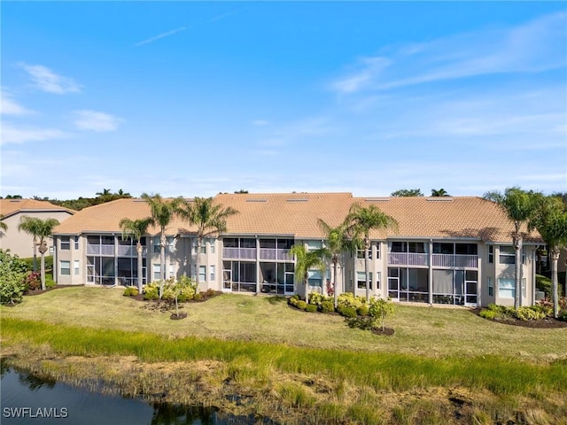 rear view of house featuring a water view and a yard