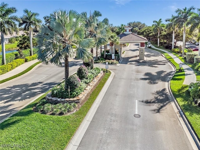 view of road featuring sidewalks, a gated entry, and curbs