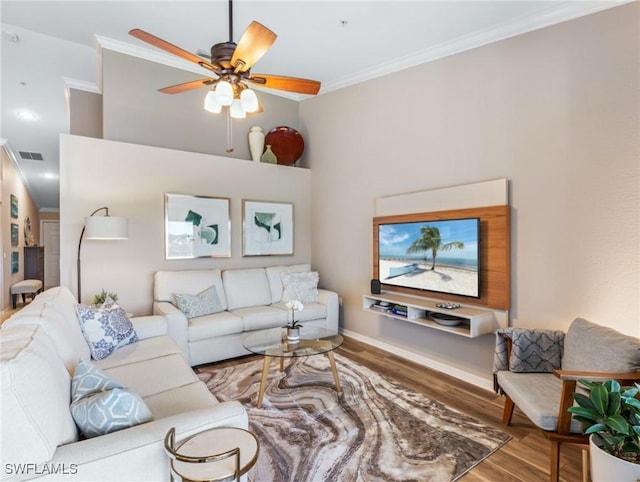 living room featuring wood finished floors, visible vents, baseboards, a ceiling fan, and ornamental molding