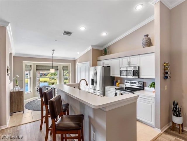 kitchen featuring appliances with stainless steel finishes, light countertops, ornamental molding, and a breakfast bar area