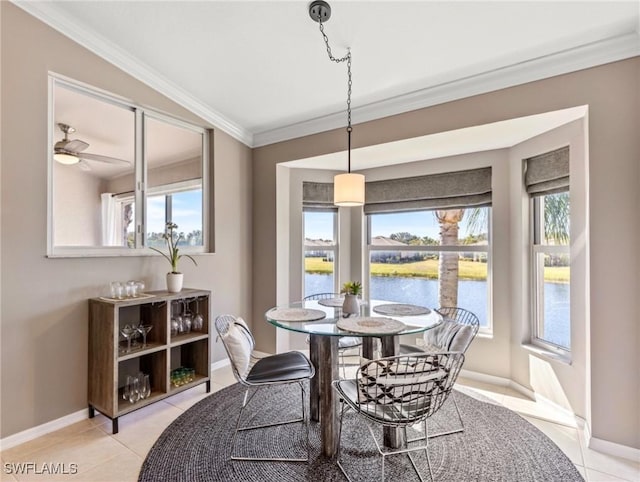 tiled dining space with crown molding, a healthy amount of sunlight, and a water view