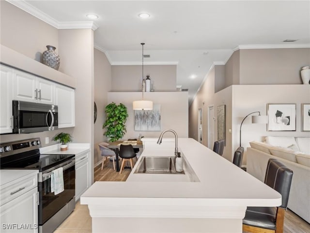 kitchen with a center island with sink, appliances with stainless steel finishes, light countertops, crown molding, and a sink