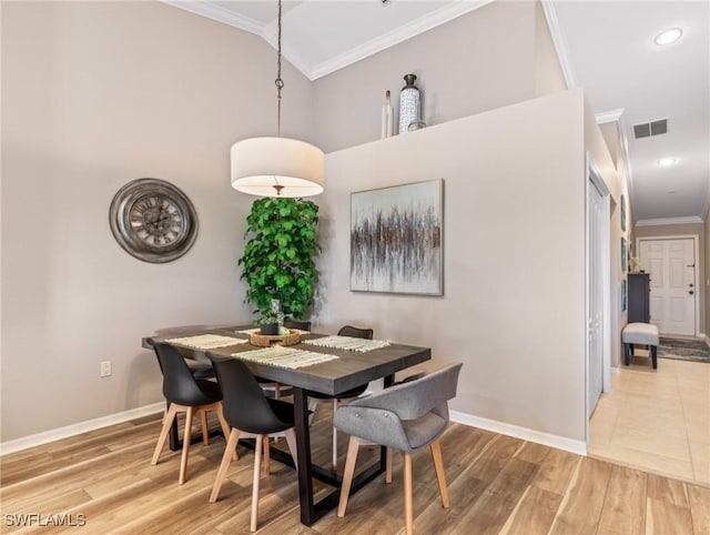 dining space featuring crown molding, lofted ceiling, and light wood-type flooring