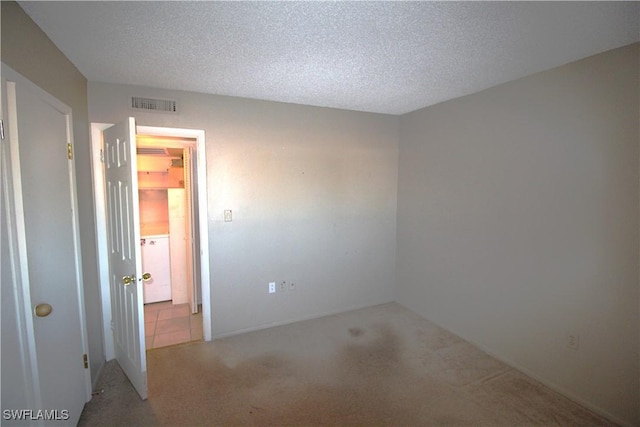 carpeted empty room featuring a textured ceiling