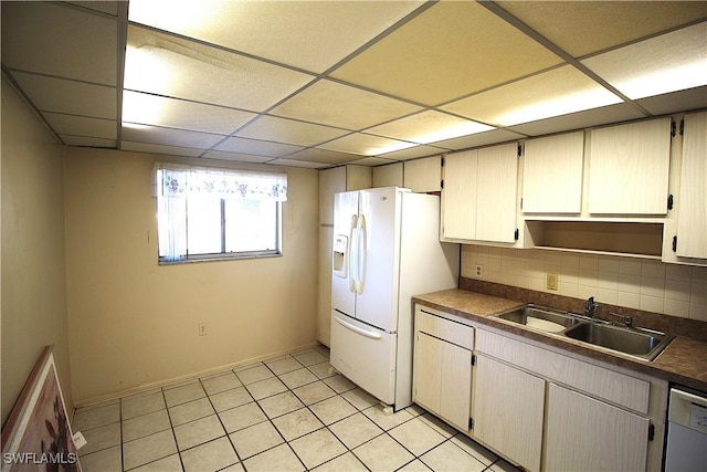 kitchen featuring tasteful backsplash, sink, light tile patterned floors, a drop ceiling, and white appliances