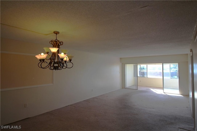 empty room featuring an inviting chandelier, carpet floors, and a textured ceiling