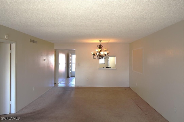 spare room with an inviting chandelier and a textured ceiling