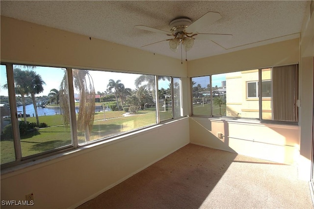 unfurnished sunroom with plenty of natural light, ceiling fan, and a water view