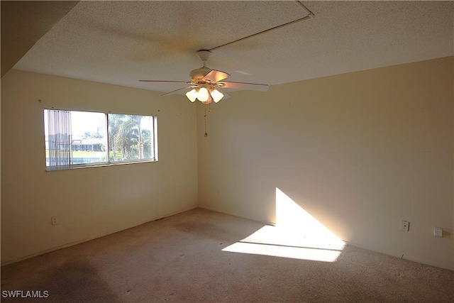 carpeted empty room featuring ceiling fan and a textured ceiling