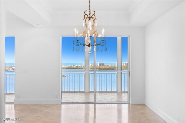 unfurnished dining area featuring a water view, a notable chandelier, and a tray ceiling