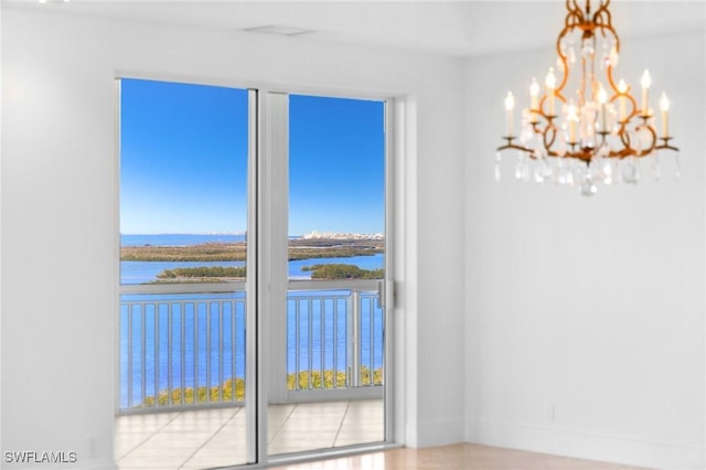 spare room with a water view and a chandelier