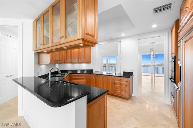 kitchen featuring dark stone countertops, sink, a kitchen breakfast bar, and kitchen peninsula