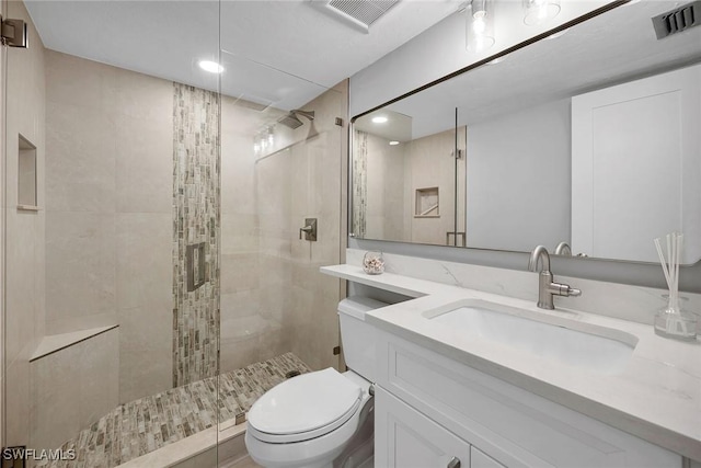 bathroom featuring vanity, toilet, and a tile shower