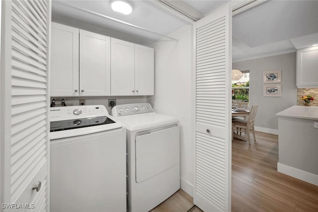 washroom with cabinets, crown molding, light hardwood / wood-style flooring, and washer and dryer