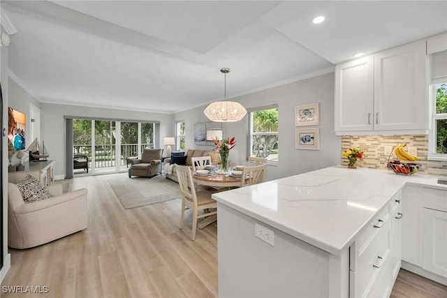 kitchen with white cabinetry, light hardwood / wood-style flooring, backsplash, and kitchen peninsula