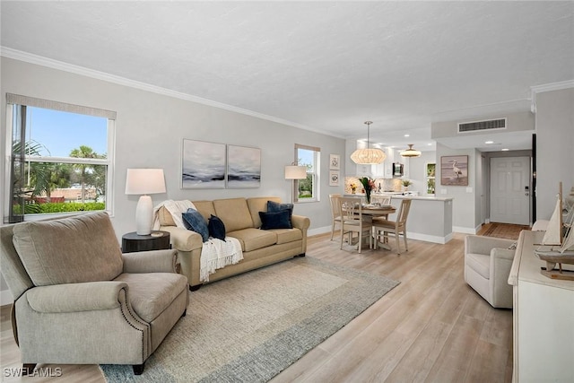 living room with ornamental molding, plenty of natural light, and light hardwood / wood-style flooring