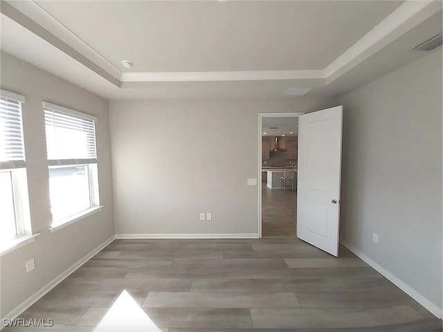 unfurnished room with hardwood / wood-style floors and a tray ceiling