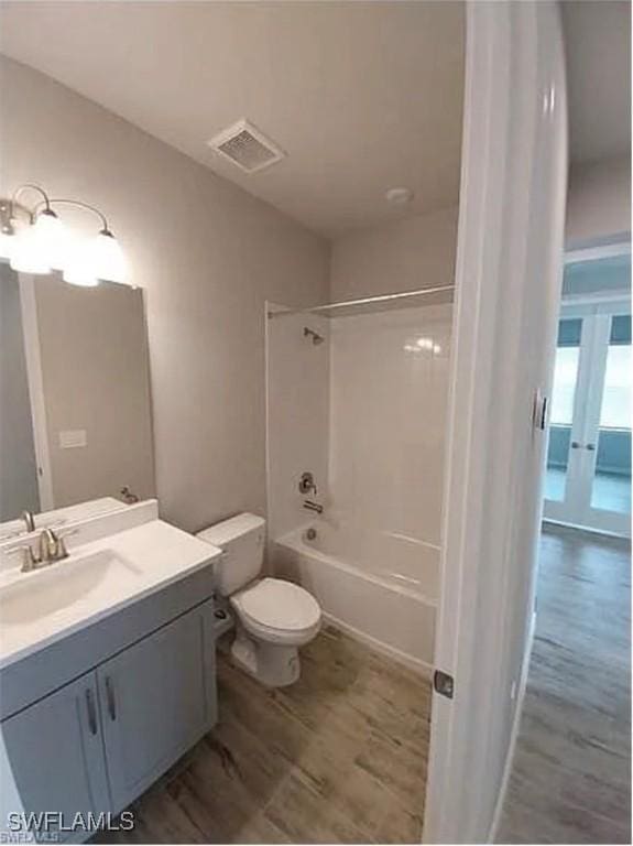 full bathroom featuring vanity, hardwood / wood-style flooring, bathtub / shower combination, and toilet