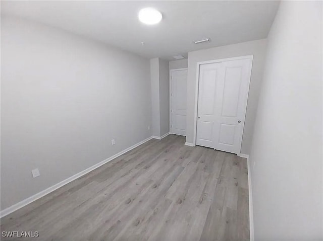 unfurnished bedroom with light wood-type flooring and a closet