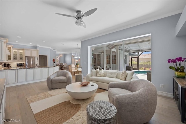 living room with crown molding, light hardwood / wood-style floors, and ceiling fan