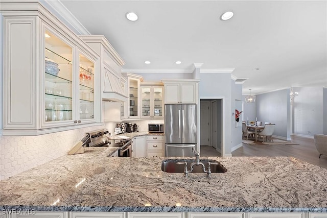 kitchen featuring sink, appliances with stainless steel finishes, backsplash, light stone countertops, and kitchen peninsula